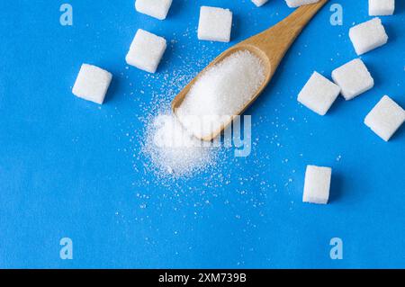 Heap of white granulated sugar with sugar cube on blue background Stock Photo