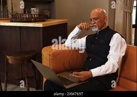 Indian Man Using Laptop At Home Stock Photo