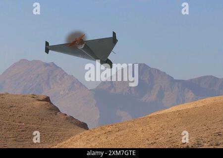 A military kamikaze drone flies over mountains in the desert against a backdrop of sky and clouds, war in Israel Stock Photo