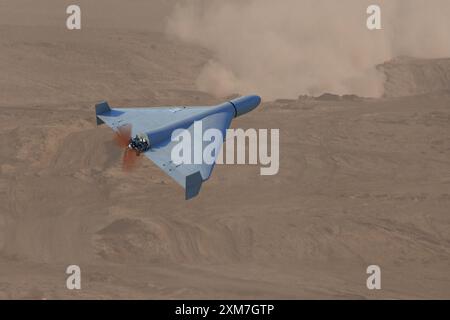 A military kamikaze drone flies over mountains in the desert against a backdrop of sky and clouds, war in Israel Stock Photo