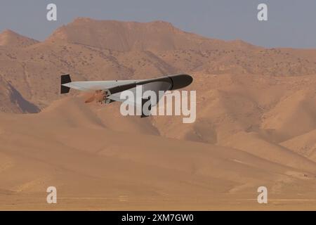 A military kamikaze drone flies over mountains in the desert against a backdrop of sky and clouds, war in Israel Stock Photo