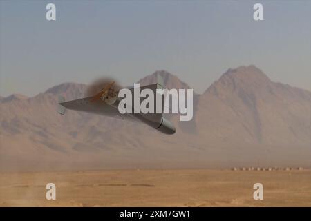 A military kamikaze drone flies over mountains in the desert against a backdrop of sky and clouds, war in Israel Stock Photo