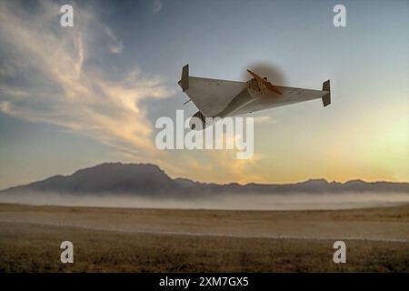 A military kamikaze drone flies over mountains in the desert against a backdrop of sky and clouds, war in Israel Stock Photo