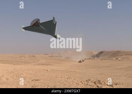 A military kamikaze drone flies over mountains in the desert against a backdrop of sky and clouds, war in Israel Stock Photo