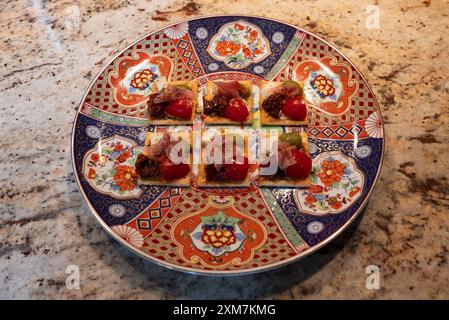 Selection of homemade snack appetizers with fresh italian ingredients. A delicious dish served on oriental style decorated colorful plate, on a light Stock Photo