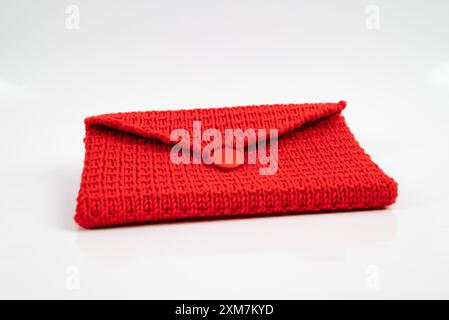 Red knitted purse, a creative handmade accessory in soft wool. This stylish and trendy needlework can make women happy. Stock Photo