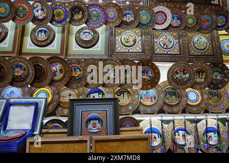 Colorful handcrafted decorative plates and framed art on display at a traditional souvenir shop in Uzbekistan Stock Photo