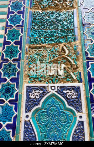Intricate Islamic geometric and floral tile patterns in blue and turquoise with visible aging and erosion on an ancient wall in Samarkand, Uzbekistan Stock Photo
