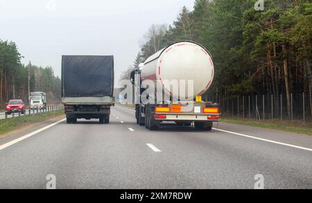 A truck with a semi-trailer tanker transports dangerous cargo along the highway - liquefied gas. Logistics of dangerous goods Stock Photo