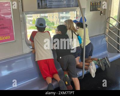 KIds look out above ground subway window on their way to Coney Island during the summer in Brooklyn; New York. Stock Photo