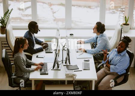 Biracial team of operators using computers and wearing headphones in call center Stock Photo