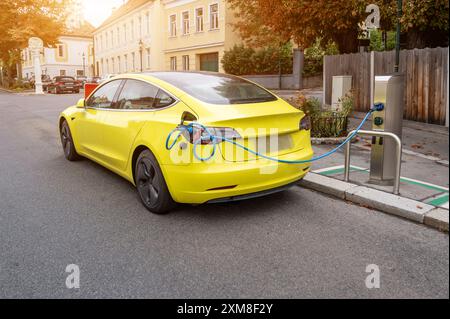 Vienna, Austria, August 22, 2022. In the village of Grinzing an electric car was parked and connected to the charging station. Modern transport techno Stock Photo