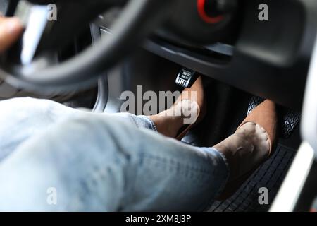 Woman in high heels pushing on pedal of car brake, closeup Stock Photo