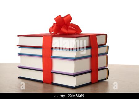 Stack of books with ribbon as gift on wooden table against white background Stock Photo