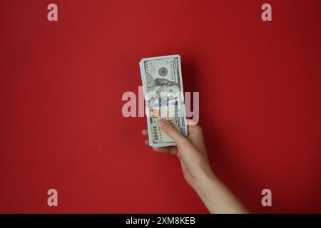 Woman with dollar banknotes on red background, closeup Stock Photo