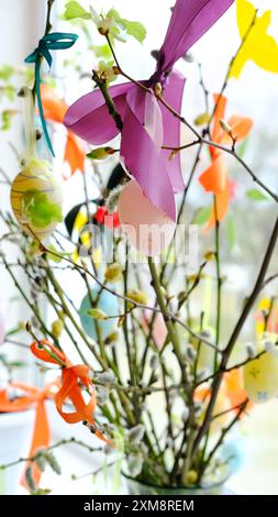 Easter eggs and colorful ribbons on willow branches in a vase, creating a festive atmosphere. Stock Photo