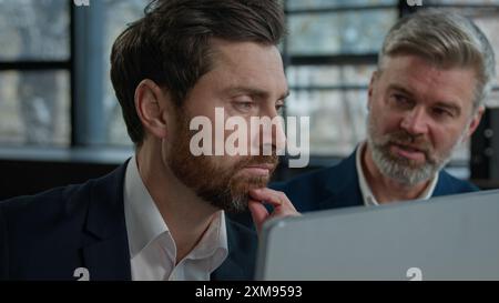 Close-up Caucasian men businessmen looking at computer screen in office executive businessman tell explain male colleague client investor sharing Stock Photo