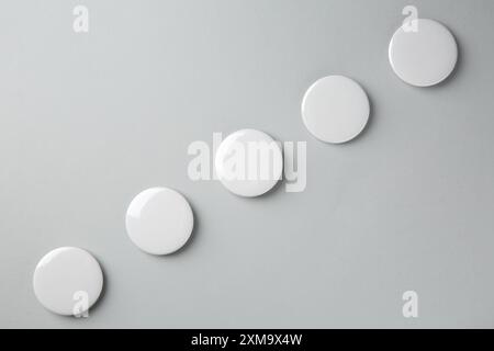 Blank white button badges on grey background, top view. Mockup for design Stock Photo