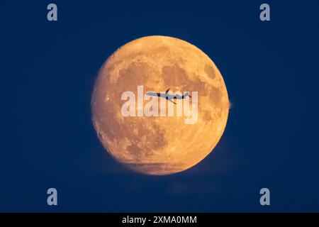 An aeroplane flies past in front of the yellow-orange full moon, Frankfurt am Main, Hesse, Germany Stock Photo