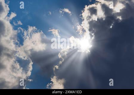 Rain clouds with sun shining through, rays of sunshine, blue sky Stock Photo