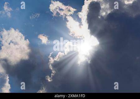 Rain clouds with sun shining through, rays of sunshine, blue sky Stock Photo