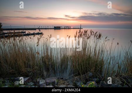 Sunrise on the shore and harbour of a lake in summer. Colourful sky with a wide view of the horiont. Natural landscape at Tihany marina, Lake Stock Photo