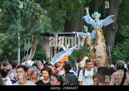 St. Petersburg, Russia. 26th July, 2024. The ceremonial procession of the street theatre festival on Elagin Island in St. Petersburg. The festival opened on the evening of July 26 with a theatrical procession from the Krestovsky Ostrov metro station to Maslyany Lug on Elagin Island. Artists in various colorful costumes performed various interactive numbers for the audience, such as dances, game numbers, improvisations, and large round dances. (Photo by Artem Priakhin/SOPA Images/Sipa USA) Credit: Sipa USA/Alamy Live News Stock Photo