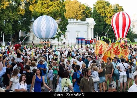 St. Petersburg, Russia. 26th July, 2024. Spectators during the ceremonial procession of the street theatre festival on Elagin Island in St. Petersburg. The festival opened on the evening of July 26 with a theatrical procession from the Krestovsky Ostrov metro station to Maslyany Lug on Elagin Island. Artists in various colorful costumes performed various interactive numbers for the audience, such as dances, game numbers, improvisations, and large round dances. (Photo by Artem Priakhin/SOPA Images/Sipa USA) Credit: Sipa USA/Alamy Live News Stock Photo