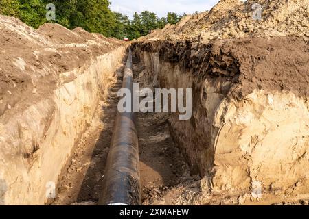 Laying of district heating pipes, next to a field, with maize, the district heating comes from a biogas plant and is fed directly into households in Stock Photo