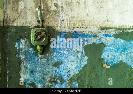 Old painted plastic rotary light switch on a grunge green peeling concrete wall background Stock Photo