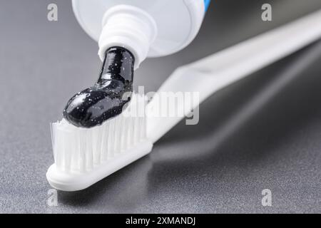 Black charcoal toothpaste being squeezed on white toothbrush Stock Photo