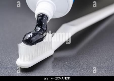 Black charcoal whitening toothpaste on white toothbrush Stock Photo