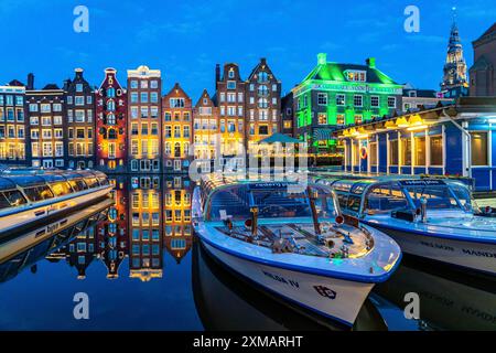 Canal houses on the Damrak, in the centre of the old town of Amsterdam, harbour, starting point of many canal tours, in the evening, church tower of Stock Photo