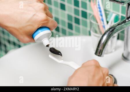Close-up view of hands of woman squeezing black toothpaste Stock Photo