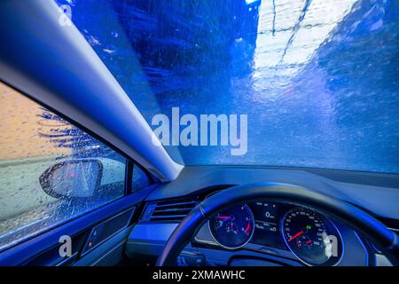 Car in an automatic car wash, car wash tunnel, cleaning foam is sprayed on, rotating brushes clean the vehicle Stock Photo