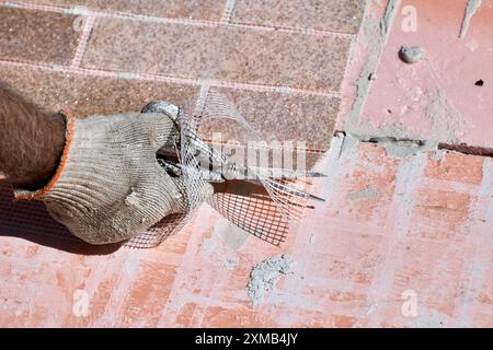 Construction worker uses scissors to cut flexible panel with imitation brickwork, made of marble chips with acrylic and reinforced with plastic mesh. Stock Photo
