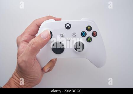 A man is holding an XBOX controller wit a white background. Stock Photo