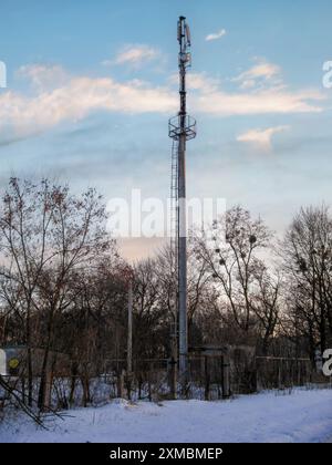 Steel telecommunications tower stands tall against a wintery landscape with a clear sky. Stock Photo