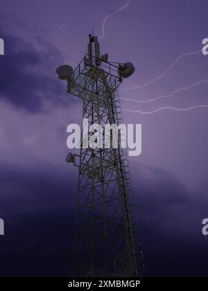 A communication tower under a dark stormy sky with visible lightning bolts. Stock Photo