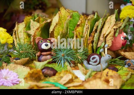 from chestnuts a bear and a snail from plasticine on autumn leaves for an autumn holiday Stock Photo