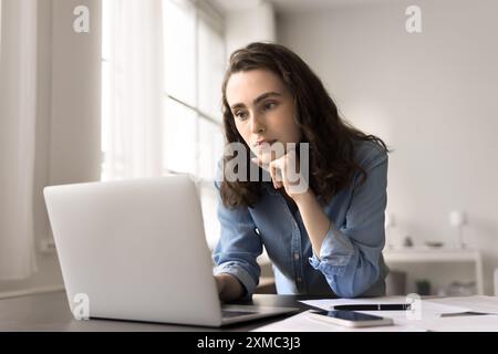 Young serious student woman or freelancer using laptop Stock Photo