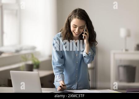 Woman talking to client, making notes, working remotely Stock Photo