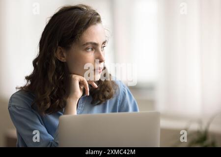Close up pensive freelance woman working on laptop Stock Photo