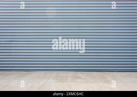 surface of gray corrugated metal factory building  facade with concrete floor. Stock Photo