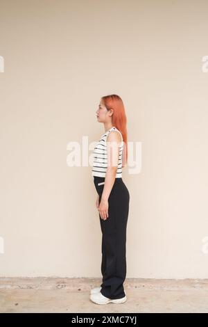 Profile View Portrait of Young Asian Woman Standing Against Plain Background Full Length Shot Stock Photo