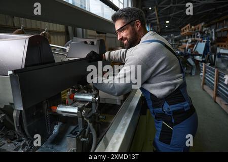 Worker in safety glasses works with aluminum profile on modern equipment Stock Photo