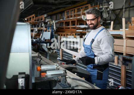 Specialist with working documentation at the console of modern machine Stock Photo