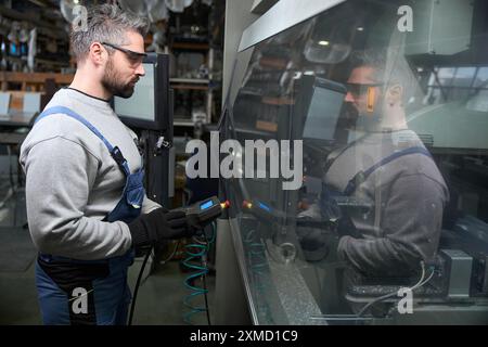 Worker uses a control panel to operate modern equipment Stock Photo