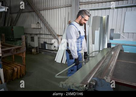 Employee of a production workshop forms bend of aluminum profile Stock Photo