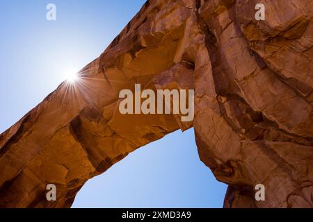 Sun peeking from behind the Pine Tree Arch in Arches National Park ...